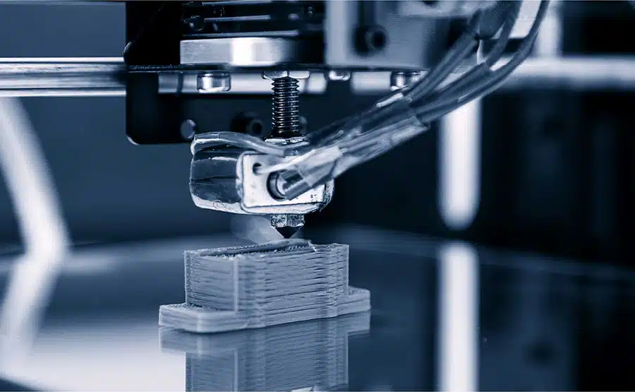 Close-up of an industrial FDM 3D printer nozzle depositing layers of engineering polymer for rapid prototyping.
