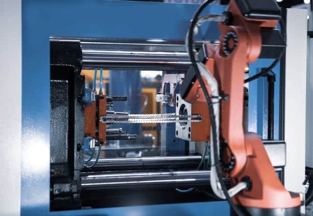 Robotic arm assisting in an automated hot runner injection molding process for high efficiency production.