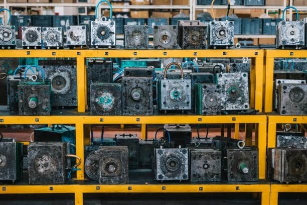 Multiple compression molding molds stored on metal racks inside a manufacturing facility.