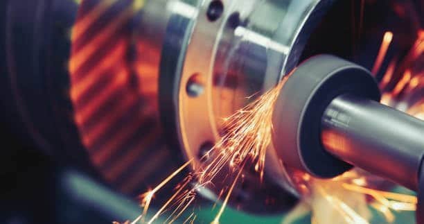 Grinding and turning operation generating sparks while finishing a cylindrical metal component