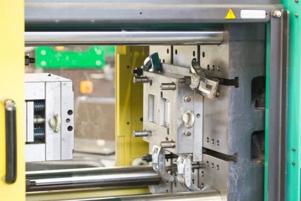 Injection molding machine with open mold chamber, showing detailed mold construction and ejector pins.