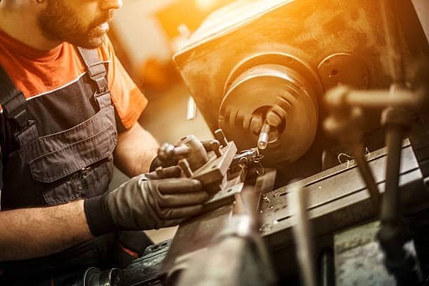 Operator setting up a manual lathe machine for turning operations