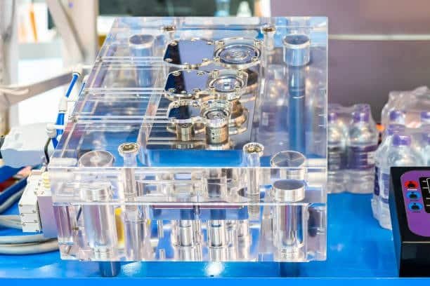 Transparent cold runner mold setup highlighting gate locations and plastic flow paths in injection molding.