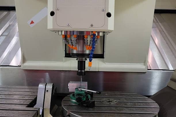 Workpiece positioned on 4-axis vertical mill with rotary table under spindle