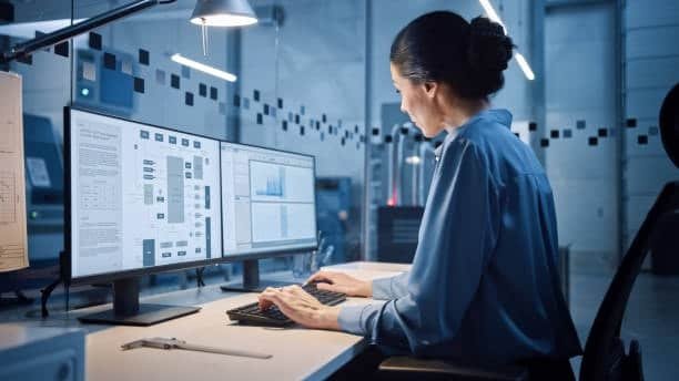 Female engineer analyzing performance data of different ABS types on dual-monitor setup