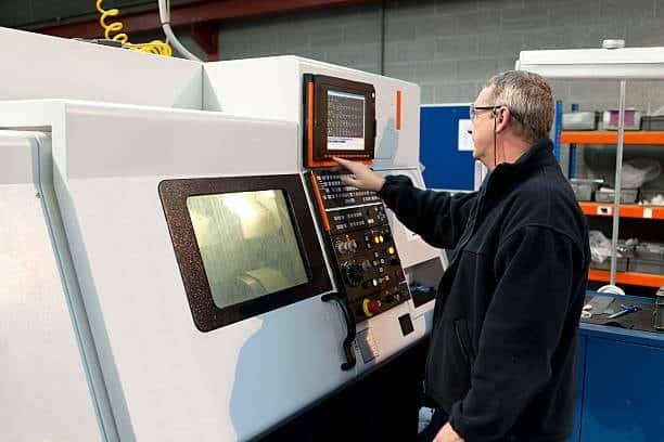 Technician programming CNC machine to fabricate parts from ABS plastic material