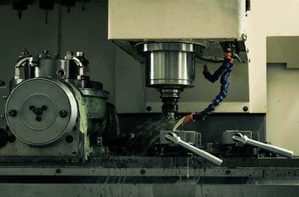 Vertical milling machine spraying coolant over a rotating part during operation, potential chatter conditions present