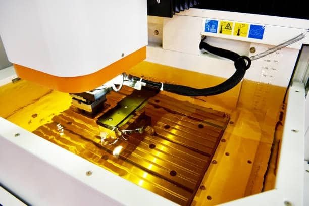 CNC EDM machine submerged in dielectric fluid during machining