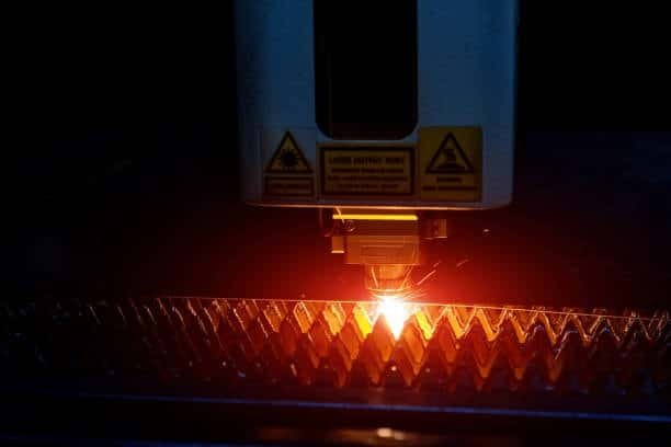 CNC laser machine cutting metal using dynamic toolpaths, producing glowing sparks and clean cuts