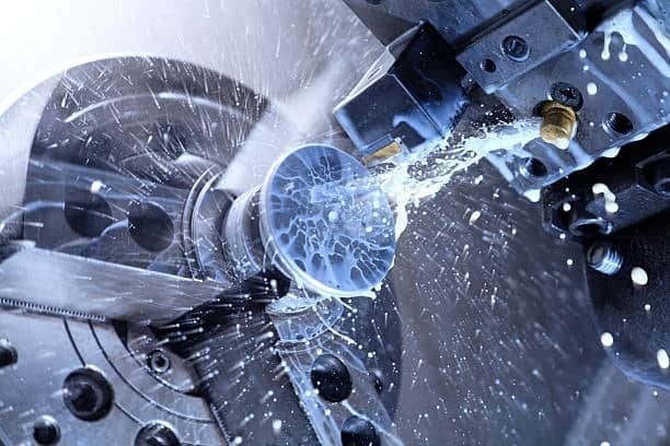 Close-up of CNC lathe spinning a metal part with coolant applied during precision turning process