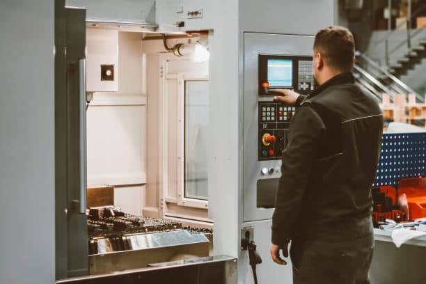 Technician adjusting CNC control panel to input dynamic toolpath parameters before machining