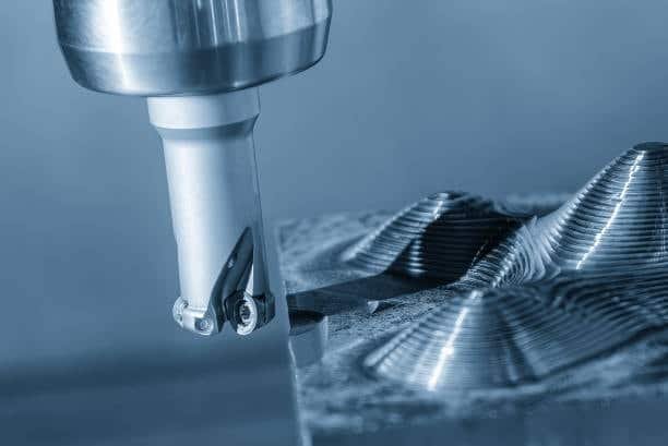 Close-up of CNC tool creating wave-shaped 3D surface contour on precision metal component