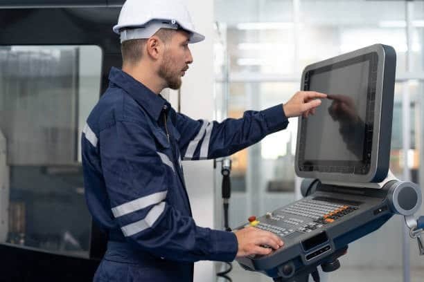 Factory worker using a modern touchscreen CNC controller in an industrial machining environment