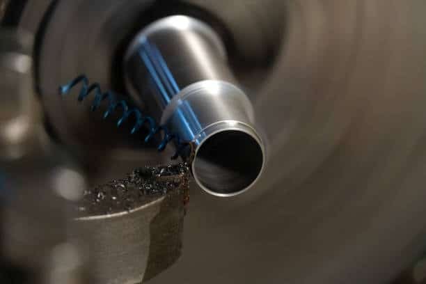 Close-up of CNC turning process with spiral chip removal and dynamic feed rate adjustments