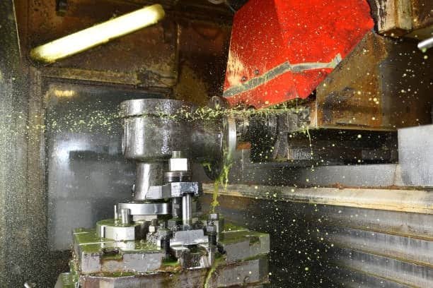 CNC vertical cutting setup with scattered lubricant and vibration-prone toolpath suggesting chatter vibration issues