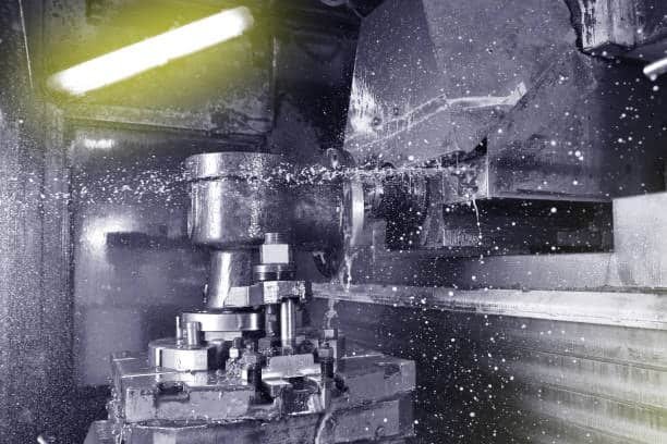 Close-up of machined part exposed to coolant spray, visible surface disruptions possibly caused by chatter