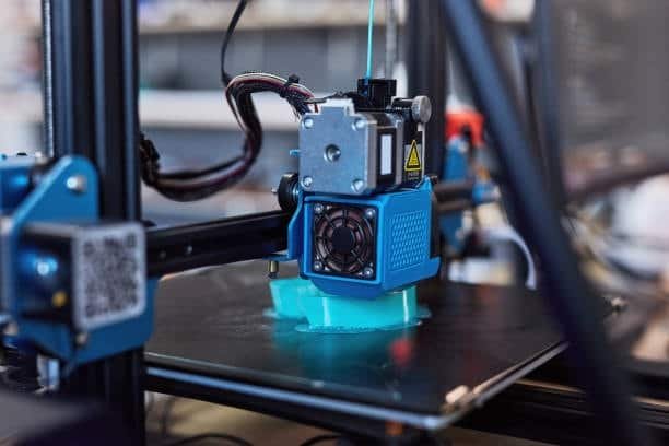 Desktop 3D printer in action producing blue plastic mold part