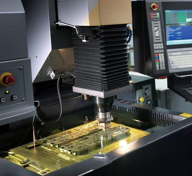 EDM machine performing spark erosion on a metal mold component