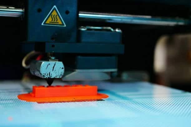 FDM 3D printer extruding orange plastic to create a mold