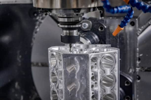 CNC machine cutting intricate aluminum block features using dynamic milling and coolant nozzles