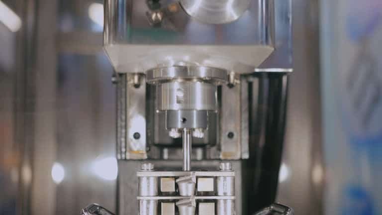 Vertical CNC milling head performing surface refinement on metal workpiece