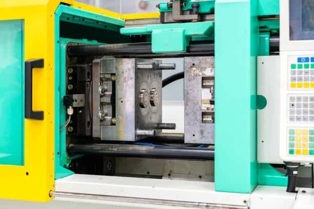 Metal injection mold tool open to show cavity and core structure inside the machine