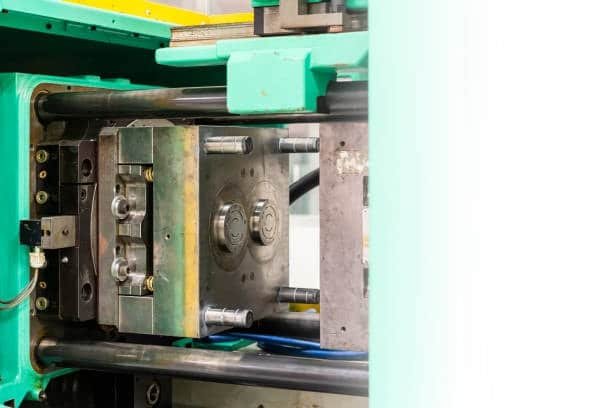 Injection molding machine holding a mold block with two circular runner-fed cavities