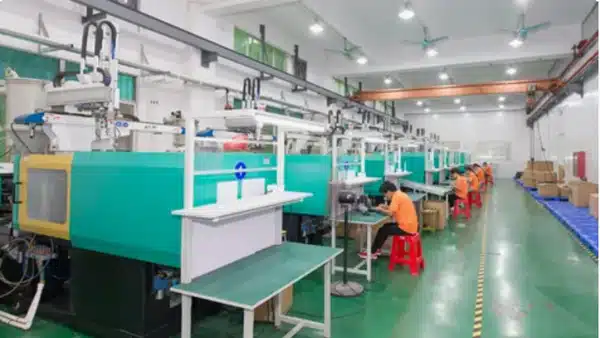 Hàng loạt máy ép phun màu xanh lá cây trong một xưởng sản xuất viễn thông sạch sẽ, với các nhân viên vận hành theo dõi quá trình sản xuất.