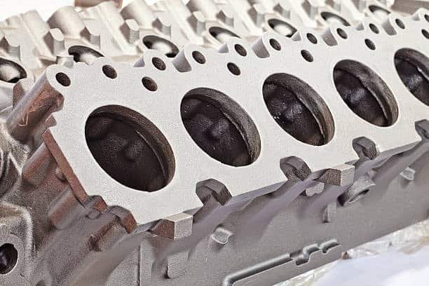 Complex automotive engine block produced using metal injection molding and finishing processes