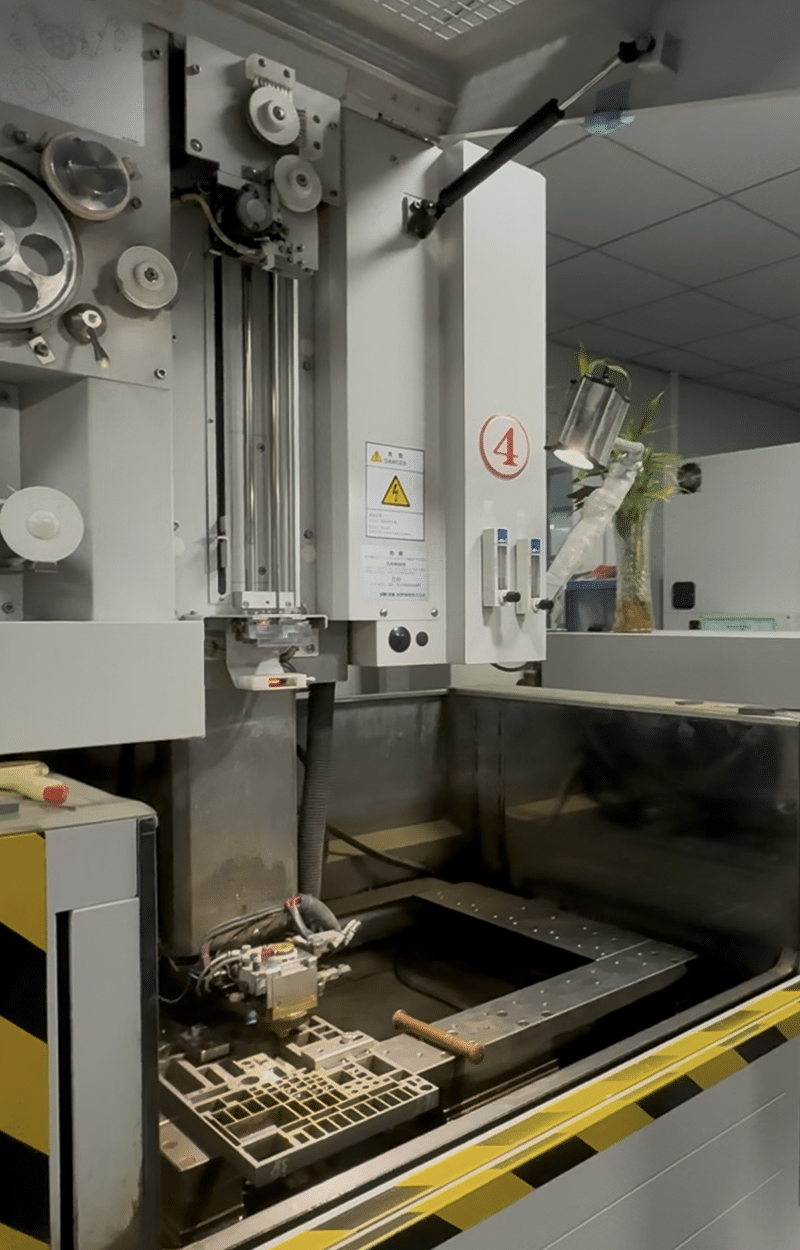 Full view of Wire EDM machine with worktable, lighting system, and mold component ready for processing