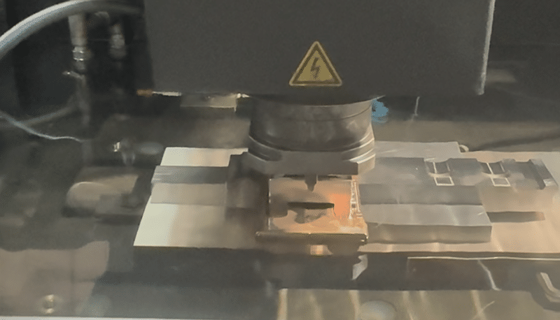 Sinker EDM machining process showing electrical discharge between electrode and workpiece in dielectric fluid
