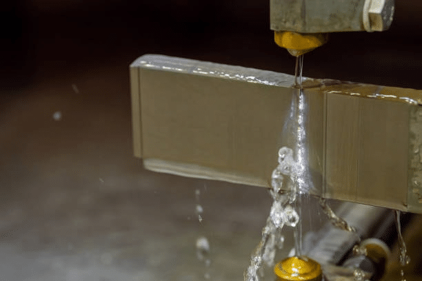 Wire EDM spark erosion cutting through a hardened steel block with dielectric fluid wash.