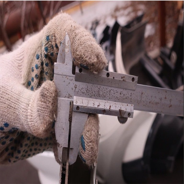 Close-up of a worker using a caliper to perform a quality inspection on a manufactured part, ensuring precise measurements.