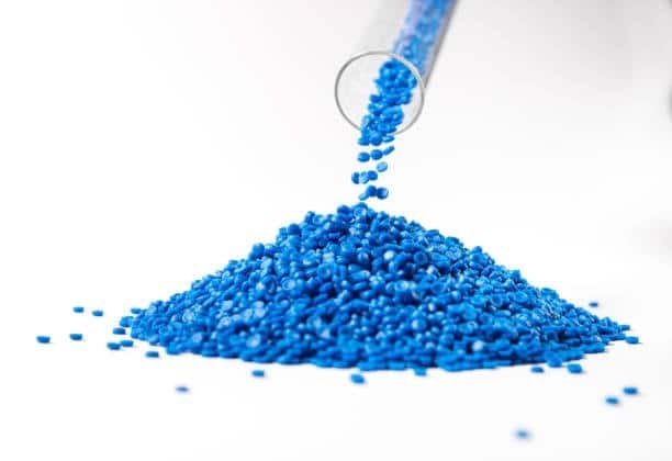 Blue thermoplastic elastomer pellets being poured from a transparent tube for lab testing or molding prep