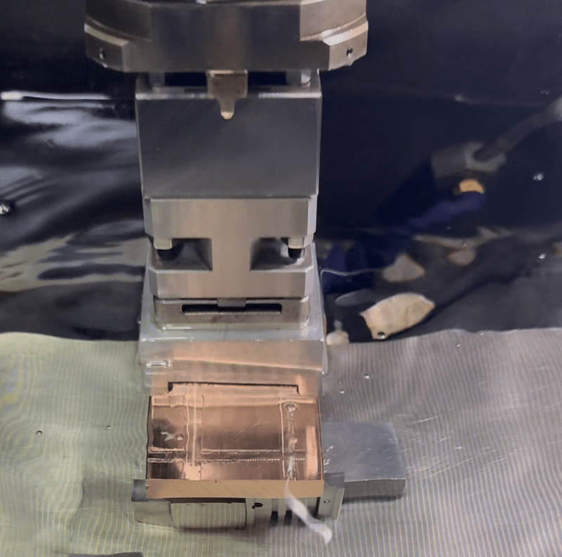 Wire EDM cutting process with fine metal wire cutting through copper workpiece in dielectric fluid