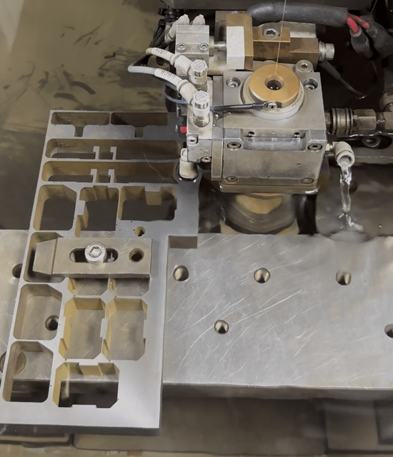 Wire EDM machine with thin metal wire feeding through guide wheels for precision cutting