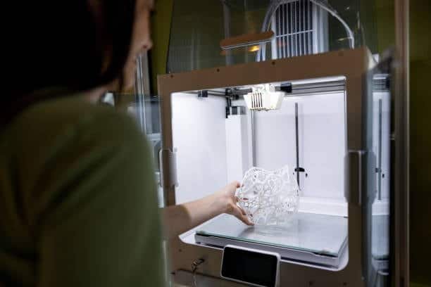 Woman retrieving a 3D printed geometric mold from the printer bed