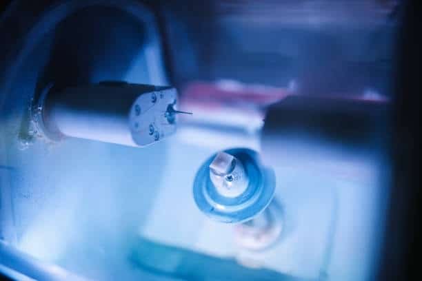 Dental milling machine crafting ABS prototype with automated tooling in blue-lit chamber