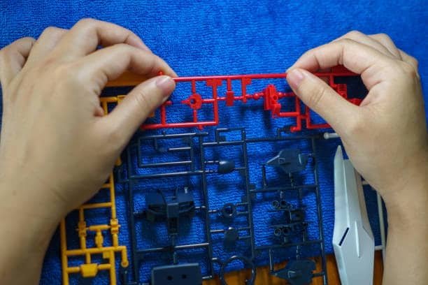 Hands holding colorful ABS injection molded plastic parts on sprue