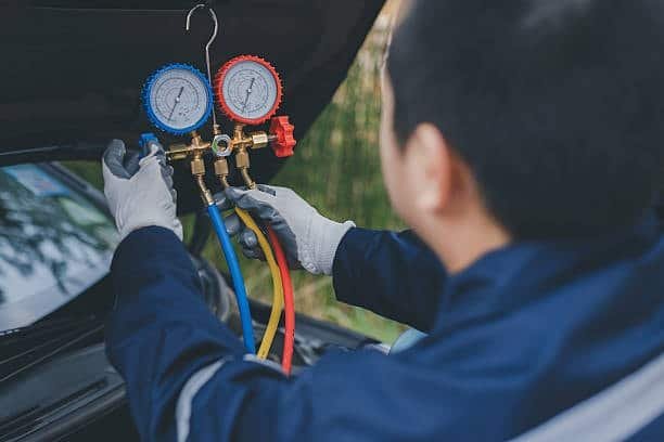 Worker connecting gauges to check fluid pressure in an automotive fixture design