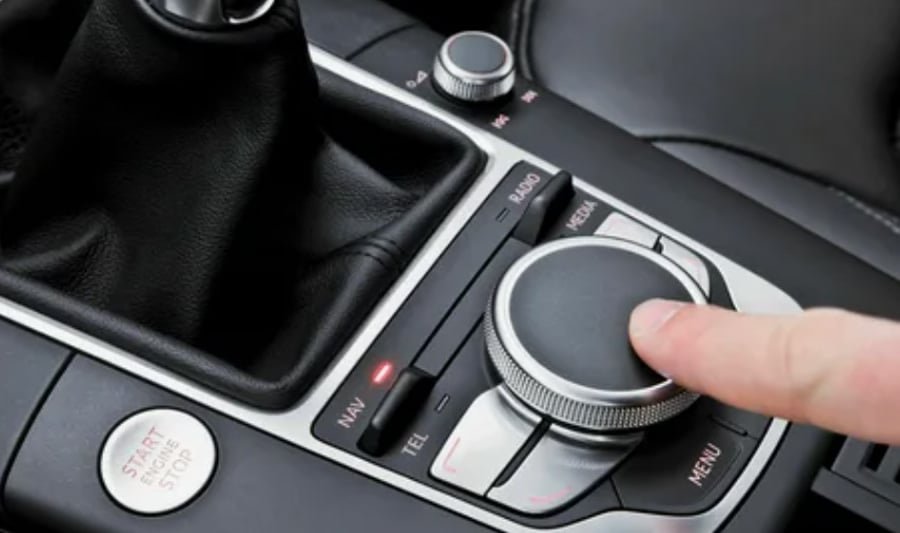 Close-up of a car’s injection-molded center console control knob and surrounding plastic trim, illustrating precision automotive interior parts.