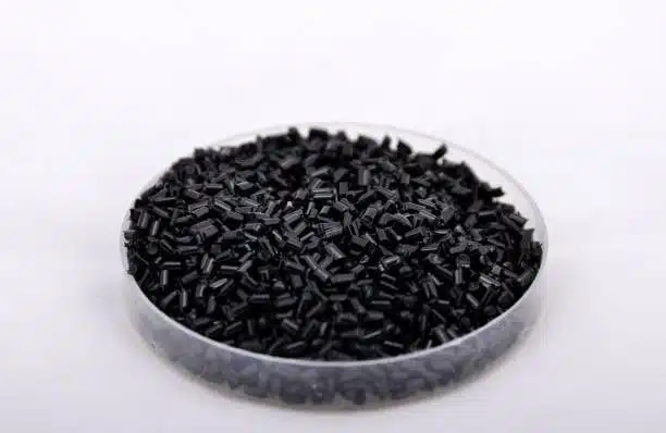 Black ABS plastic granules in a laboratory petri dish, suitable for industrial or safe product testing.