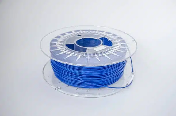 Blue polycarbonate filament wound around a transparent plastic spool, showcasing material clarity and structure.