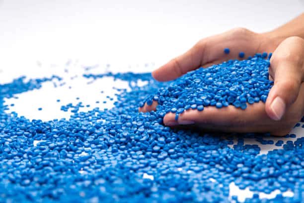Bright blue polypropylene pellets in hand, ready for plastic molding applications