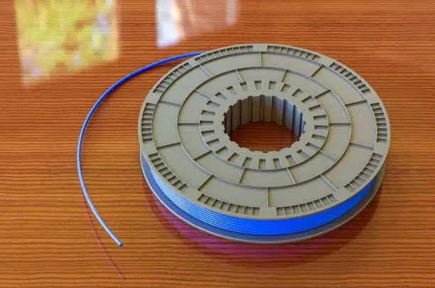 Blue polypropylene filament wound on a brown plastic spool, placed on a wooden surface.