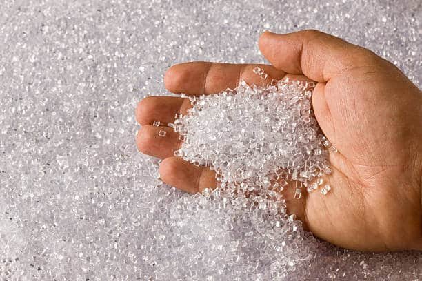 Hand holding transparent polypropylene resin granules for injection molding
