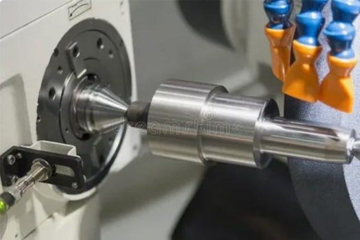 CNC grinding machine performing precision cylindrical grinding on a metal shaft for tight tolerance components.