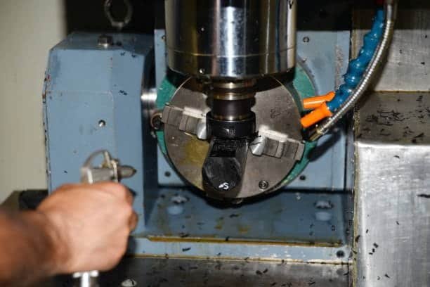 Operator adjusting a CNC chuck for precision part machinin