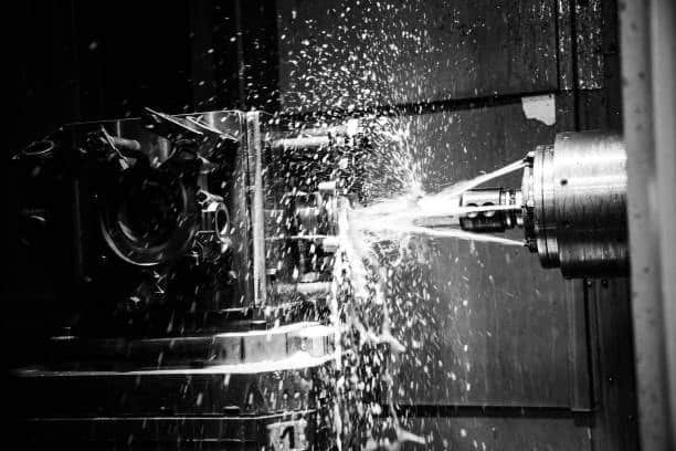 High-speed CNC lathe machine with fluid cooling system in operatio
