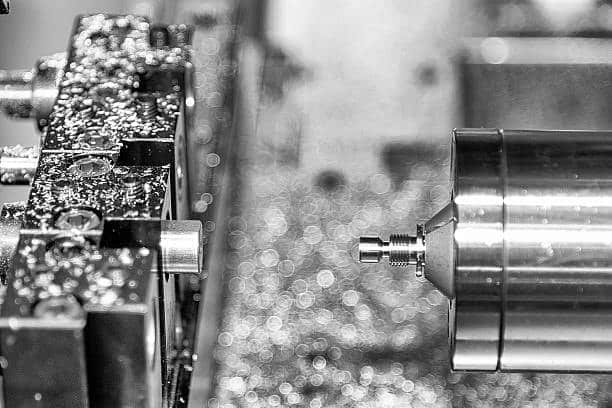 CNC lathe turning operation with metal chips and coolant in view